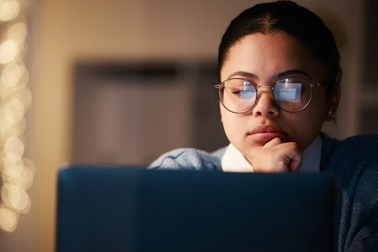 A skeptical person seen examining a computer screen.