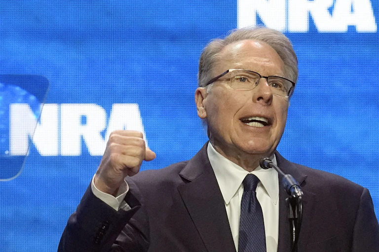 Man in suit speaks while holding up his fist.