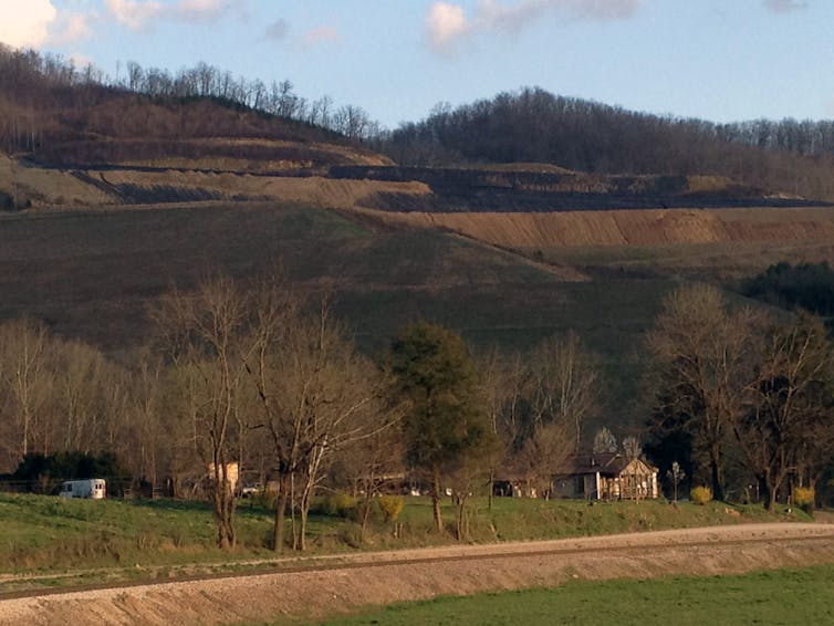 The hills above a home have been strip mined, where forests once stood.