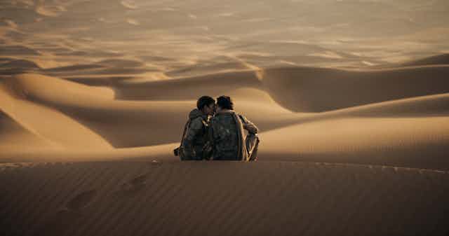 Dune production still, two people kiss on a sanddune