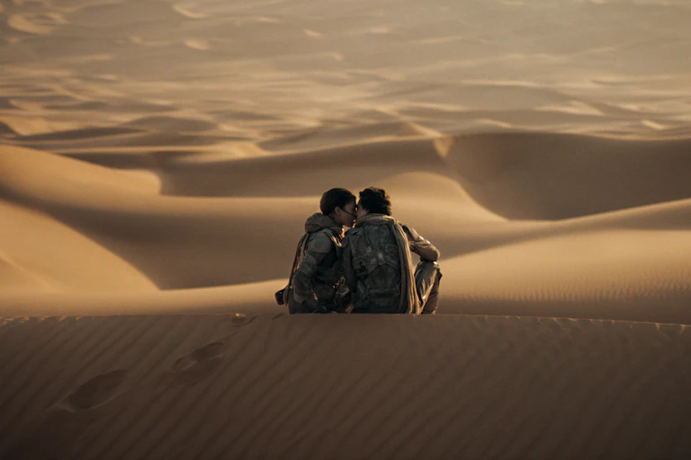 Dune production still, two people kiss on a sanddune