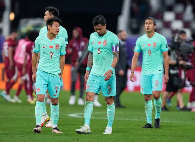 Players look dejected as they walk across a football pitch