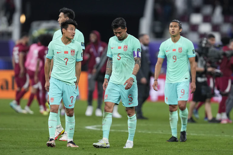 Players look dejected as they walk across a football pitch