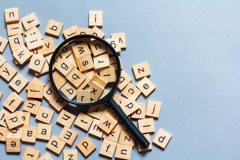 Una lupa sobre unas fichas de Scrabble con diferentes letras.