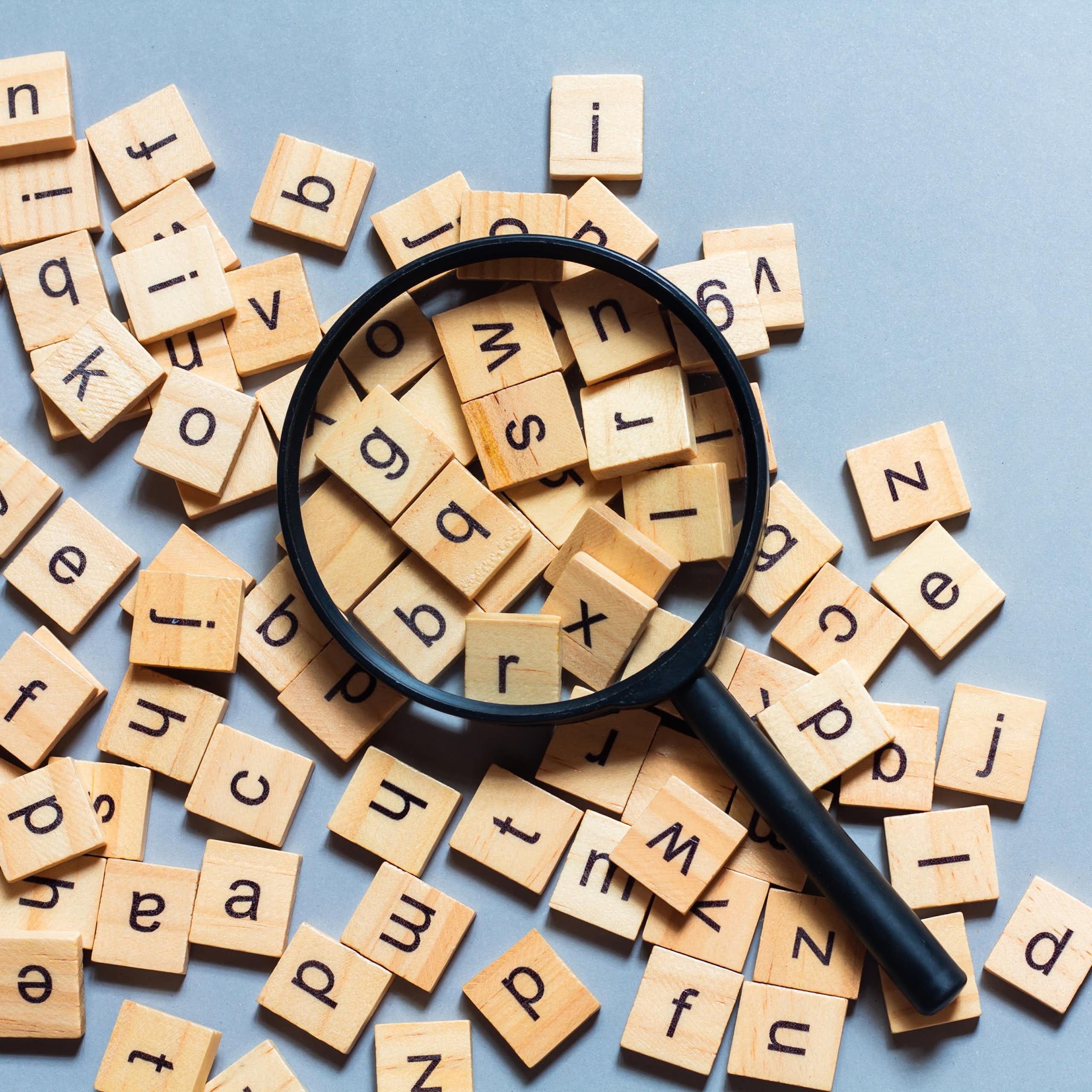 Una lupa sobre unas fichas de Scrabble con diferentes letras.