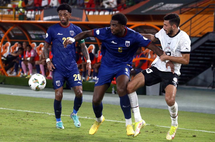 Two football players competing for control of the ball on the pitch.