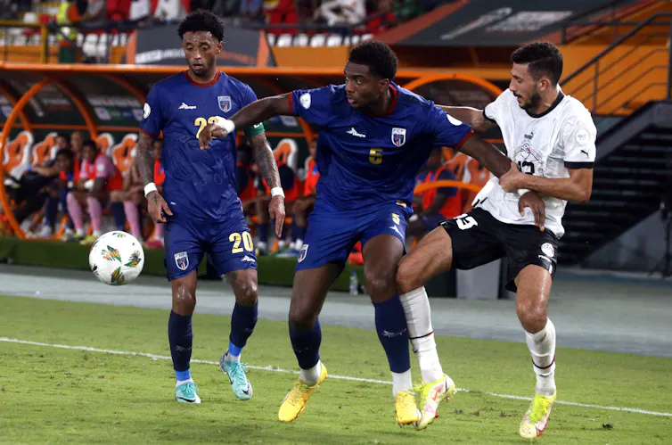Two football players competing for control of the ball on the pitch.