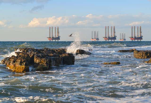 A coastal scene with five drilling platforms on the horizon.
