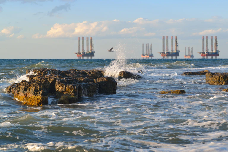 A coastal scene with five drilling platforms on the horizon.