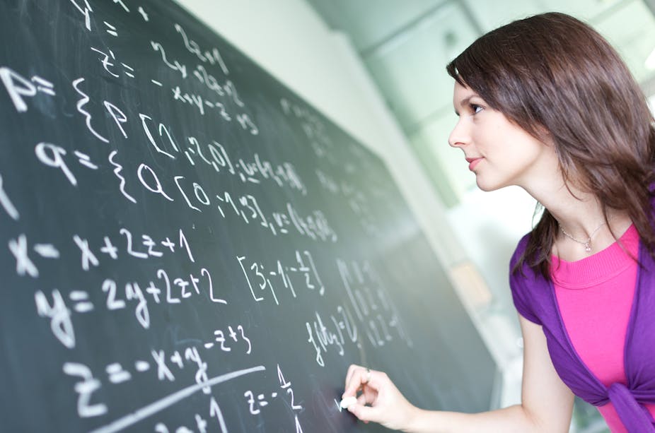 Jeune femme écrivant des formules de maths au tableau dans un amphi