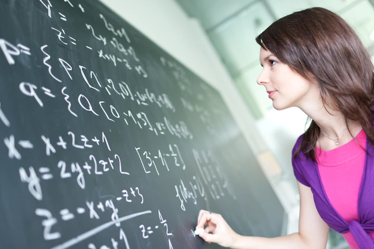 Jeune femme écrivant des formules de maths au tableau dans un amphi