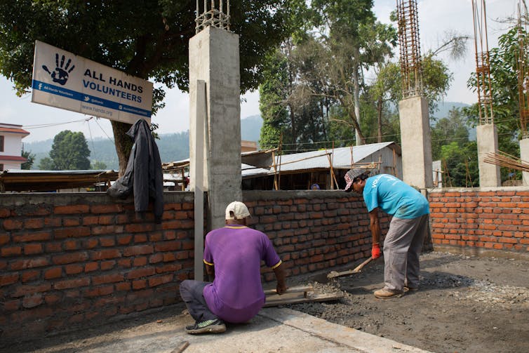 Volunteers at building site laying bricks.