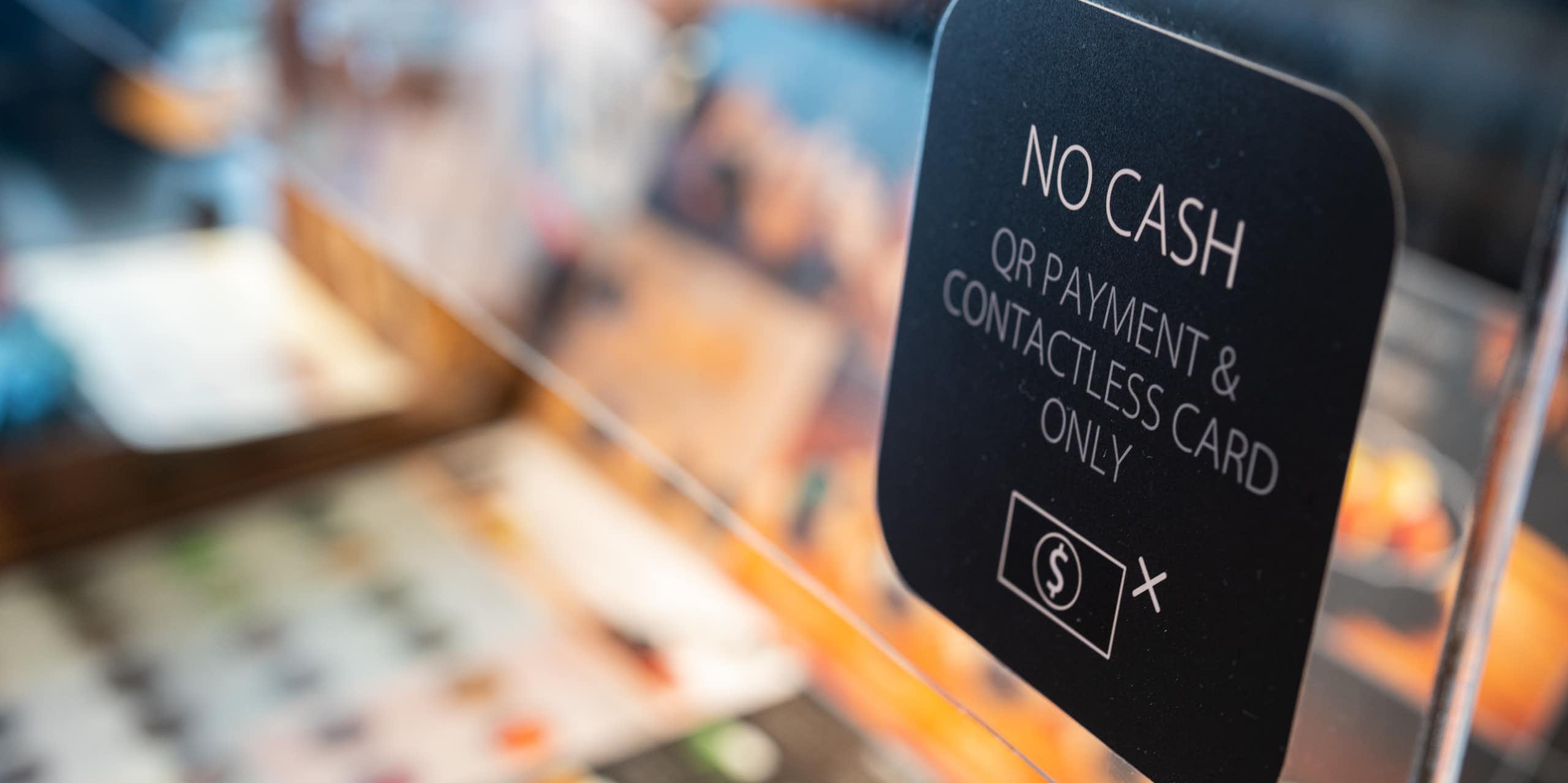 Un cartel advierte a los clientes de que sólo pueden pagar con un código QR o una tarjeta sin contacto, no en efectivo.