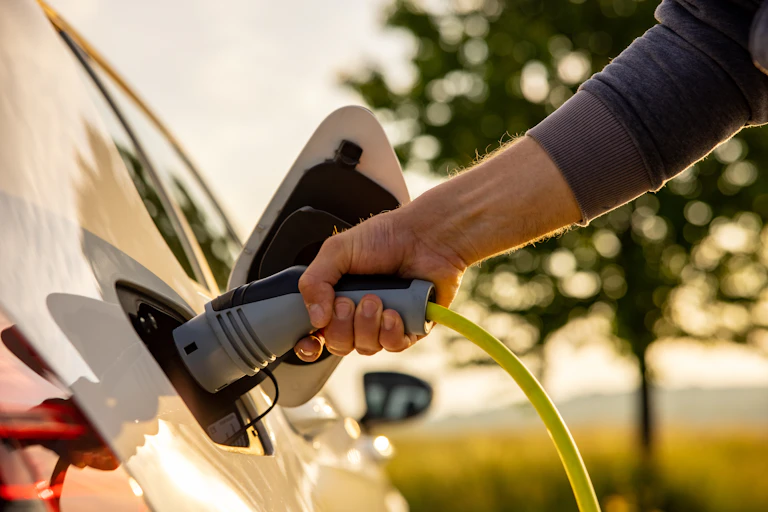A man inserts a power cord into an electric car for charging.