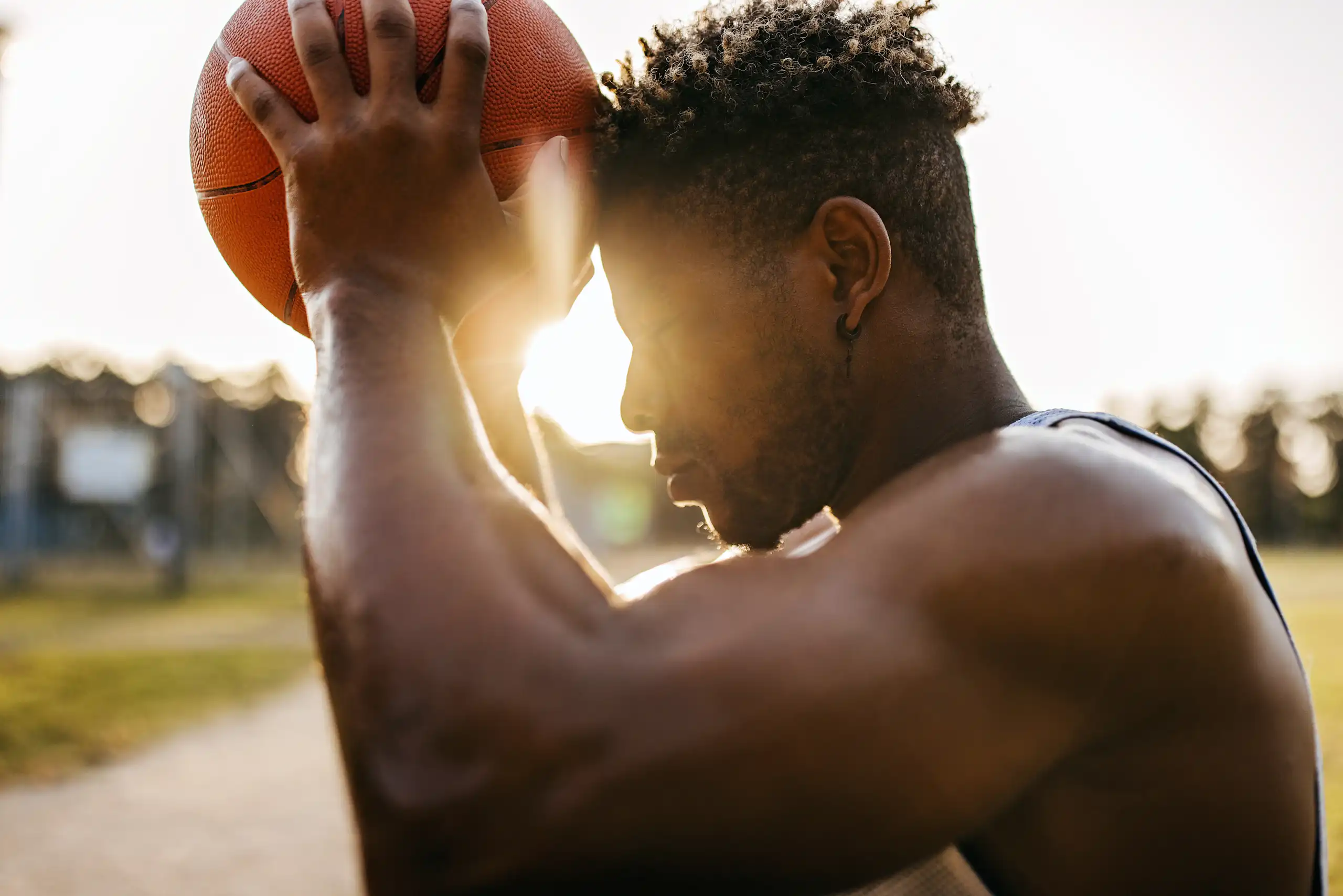Young man wearing jersey holds basketball against forehead