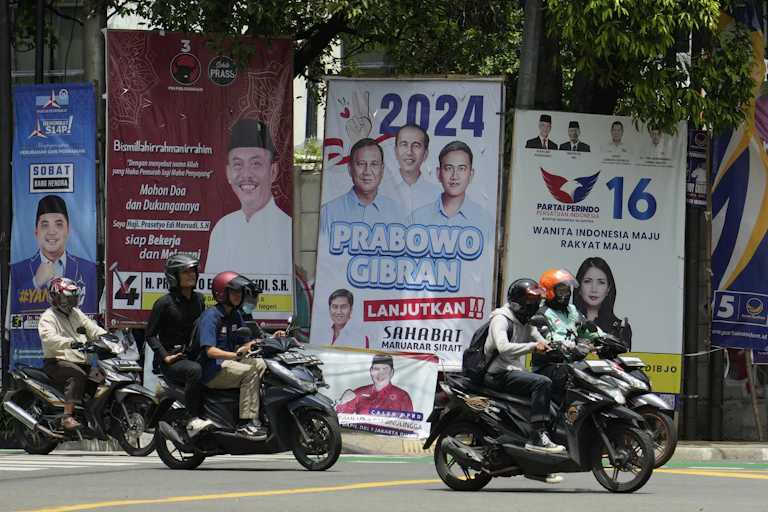 Motorists ride past political banners.
