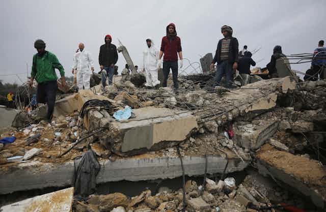 People stand amid concrete rubble from destroyed building