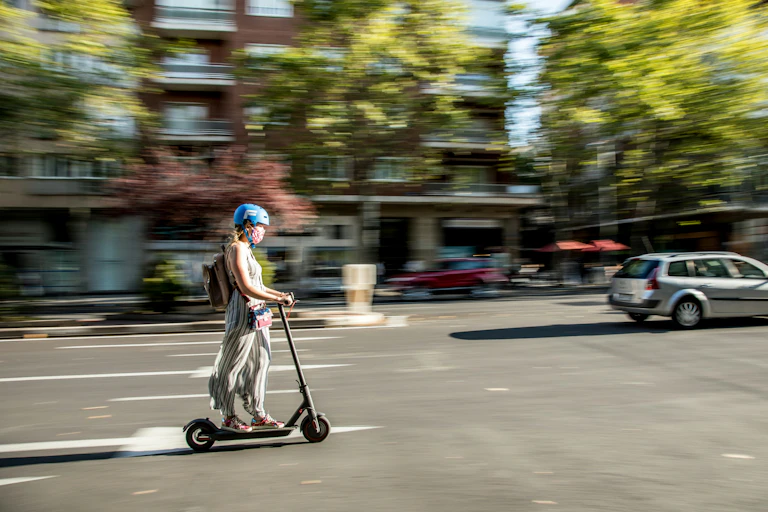 Adult woman on e-scooter on road wearing helmet