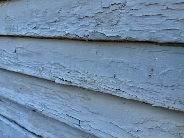 The exterior of a house, showing cracked and blistered blue paint.