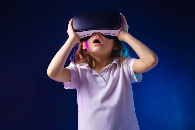A young child wearing a VR headset looking thrilled with what they see