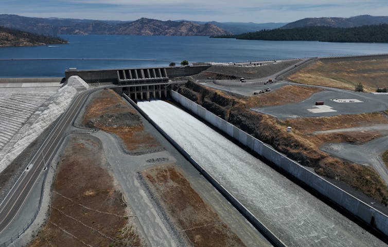 A dam spillway with a full reservoir behind it.