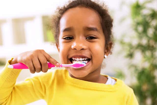 Young girl looking happy brushing her teeth