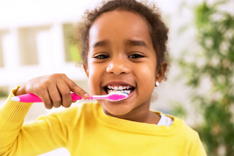 Young girl looking happy brushing her teeth