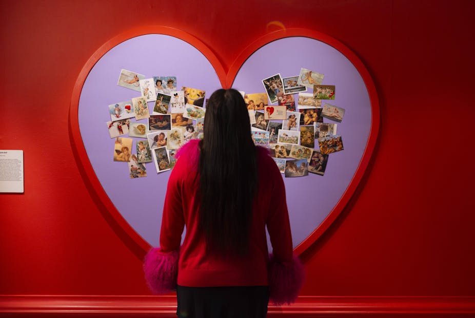 a girl looks at a giant heart filled with photos