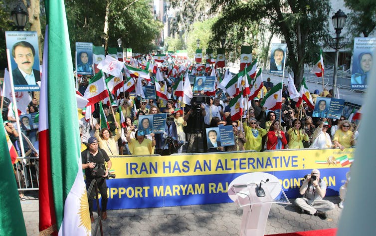 Crowds of people carrying pictures of Iranian dissidents with a banner calling for new leadership in Iran.