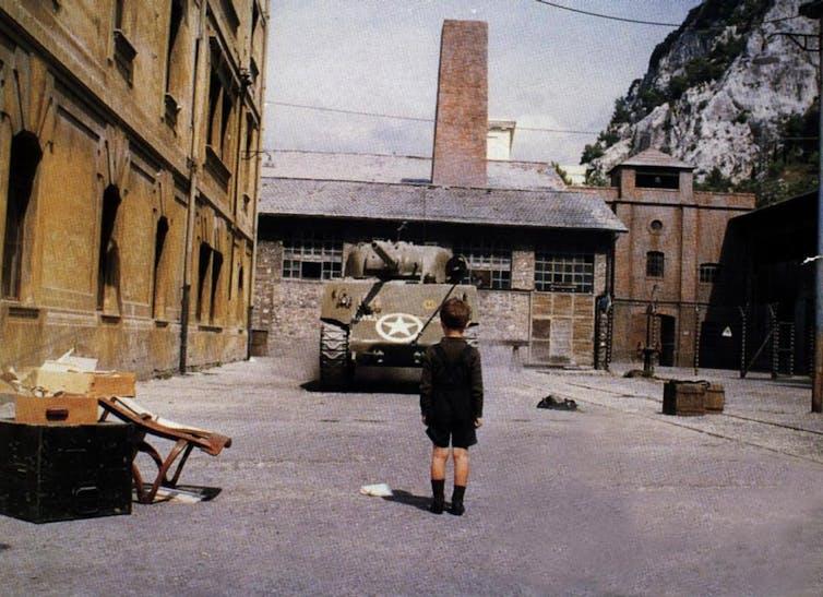 Un niño de espaldas en un espacio industrial observa un tanque.