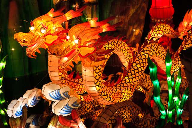 Two colorful and brightly lit dragon-shaped lanterns, with glowing eyes, on display.
