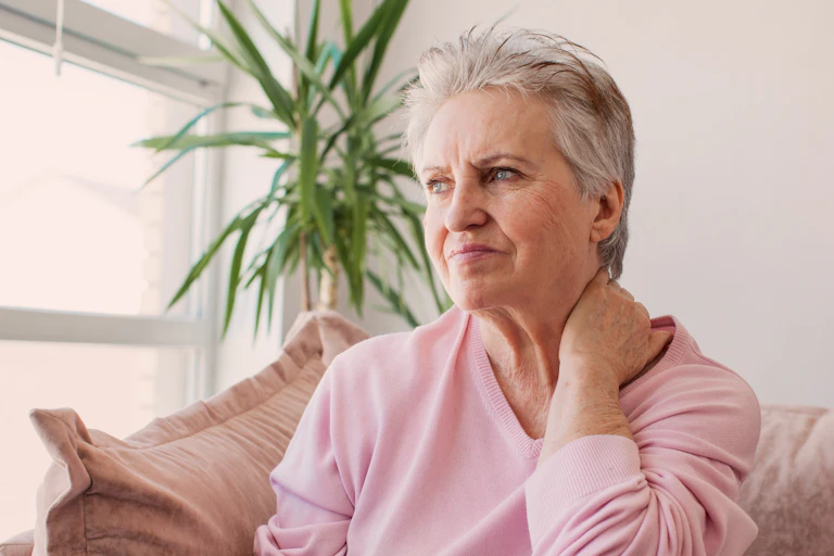 woman rubs neck with mildly concerned look on face