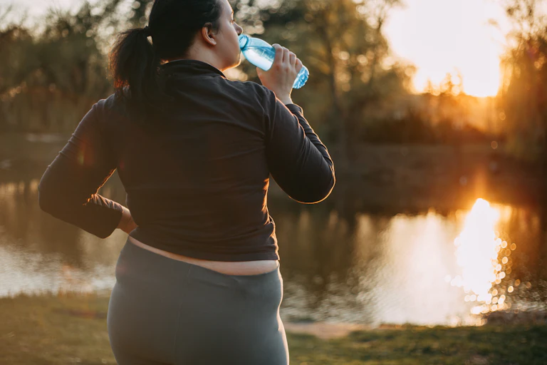 Woman drinks water looking at the sunrise