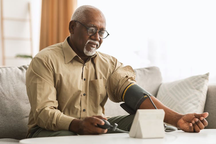 Older man takes his blood pressure at home