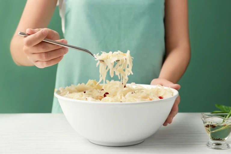 A woman holds a spoonful of sauerkraut.