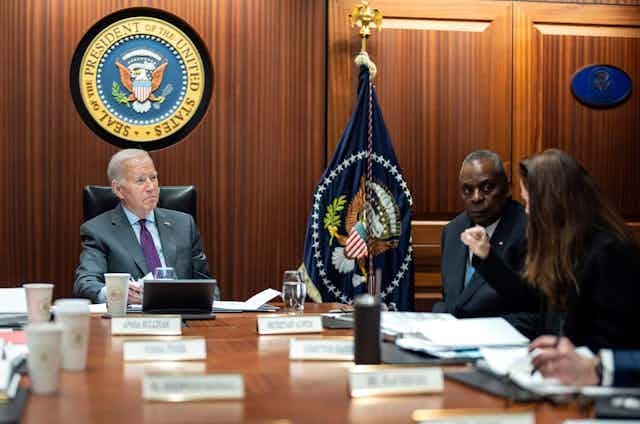 Joe Biden sits in the White House situation room under the great seal of US presidents, alongside defense secretary Lloyd Austin,receiving the daily intelligence briefing.