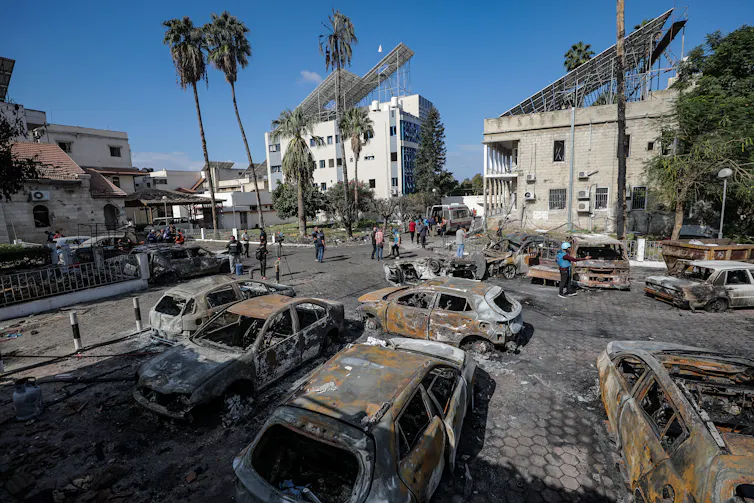 Burnt out cars in a car park on a sunny day.