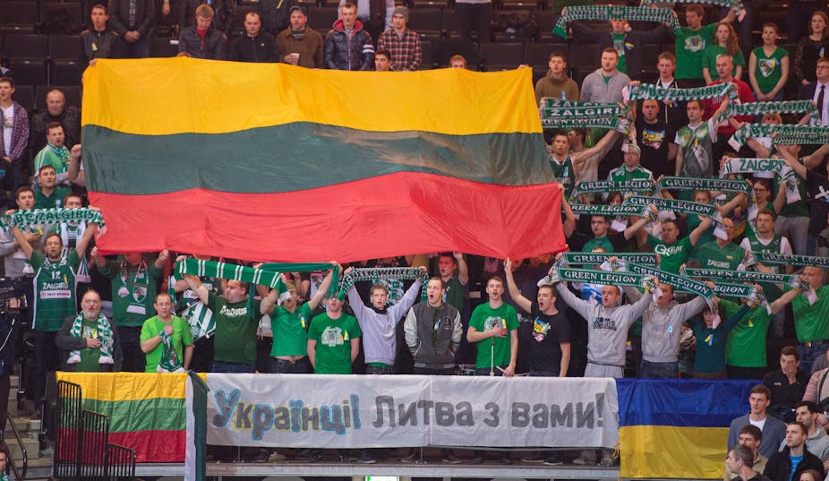 En tribune, des supporters du Zalgiris Kaunas brandissent des drapeaux lituaniens et un drapeau ukrainien, ainsi qu'une banderole proclamant en ukrainien «  Ukrainiens ! La Lituanie est avec vous ! » 