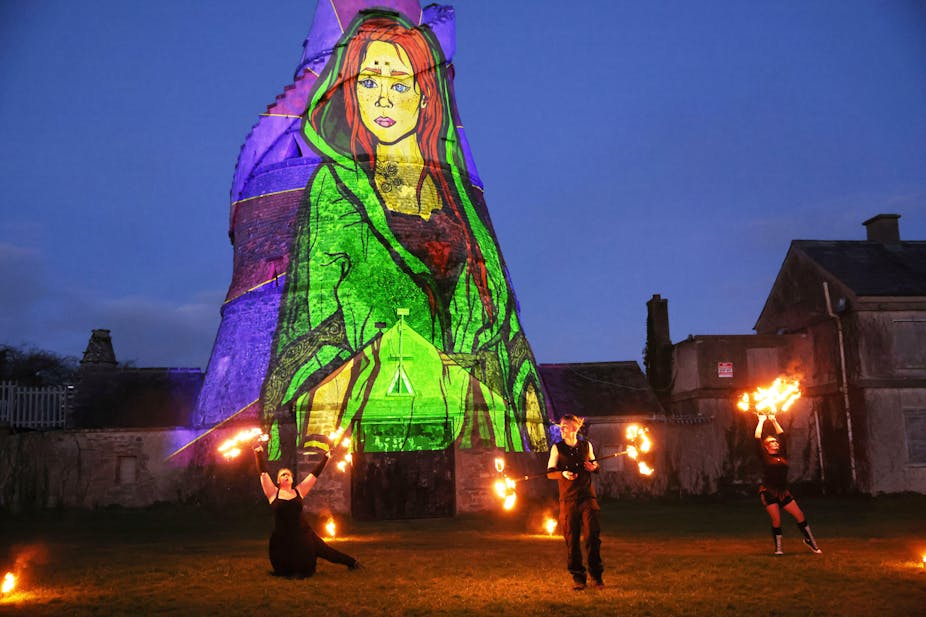 Dancers perform in front of an image of St. Brigid projected onto a barn.