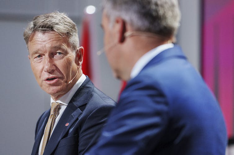 Two men stand next to each other.