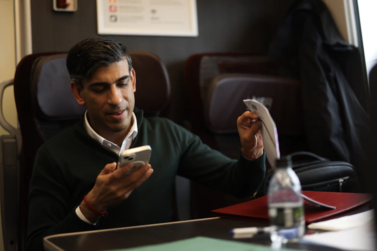 Rishi Sunal looks at his phone while sitting on a train.