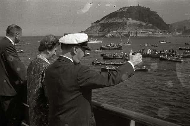 Un hombre con gorro de marinero observa una competición de regatas.