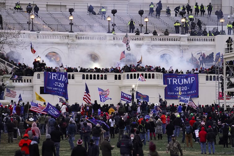 A crowd of people climb the walls and stairs of the U.S. Capitol.