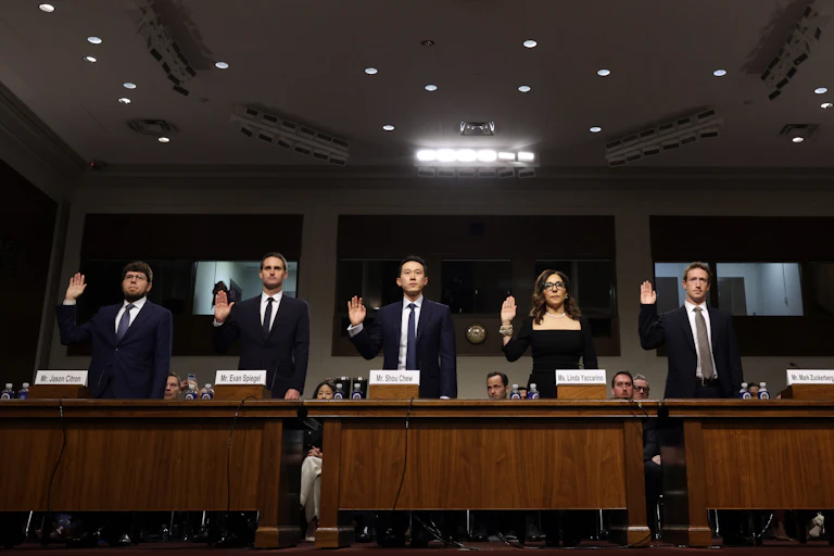 five people in business attire stand with their right hands raised
