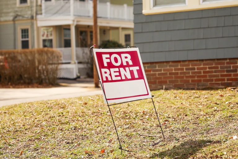 A 'for rent' sign on the front lawn of a house