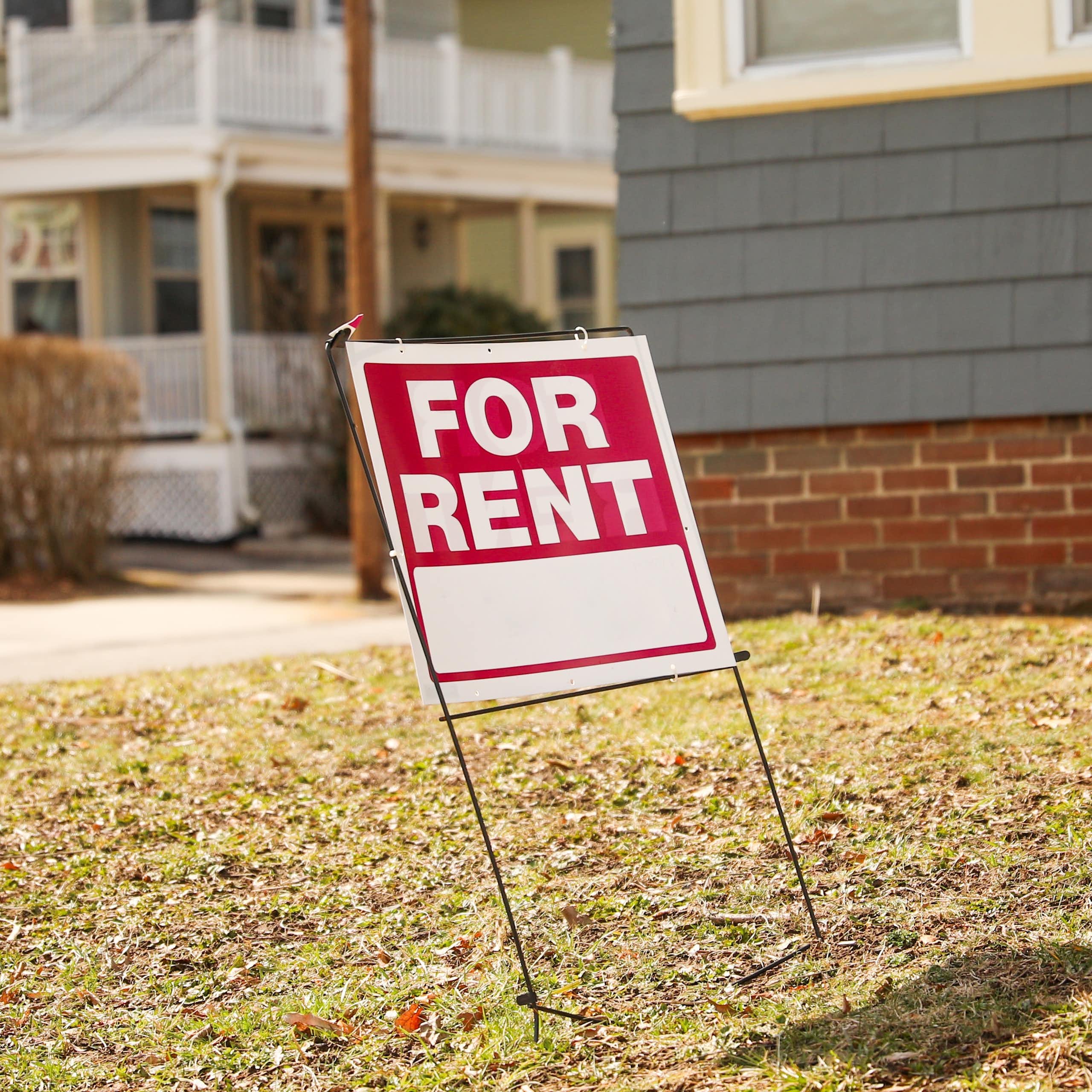 A 'for rent' sign on the front lawn of a house