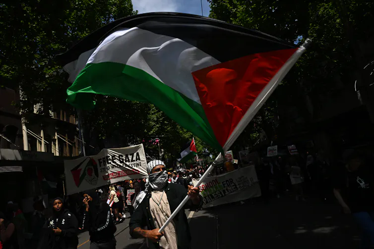A man waves a large Palestinian flag as he marches down a Melbourne street