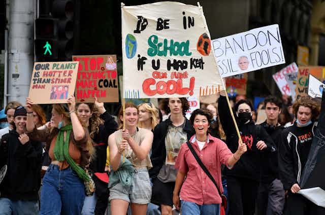 students protesting lack of climate change action, carrying banners and crossing a pedestrian crossing as a big group