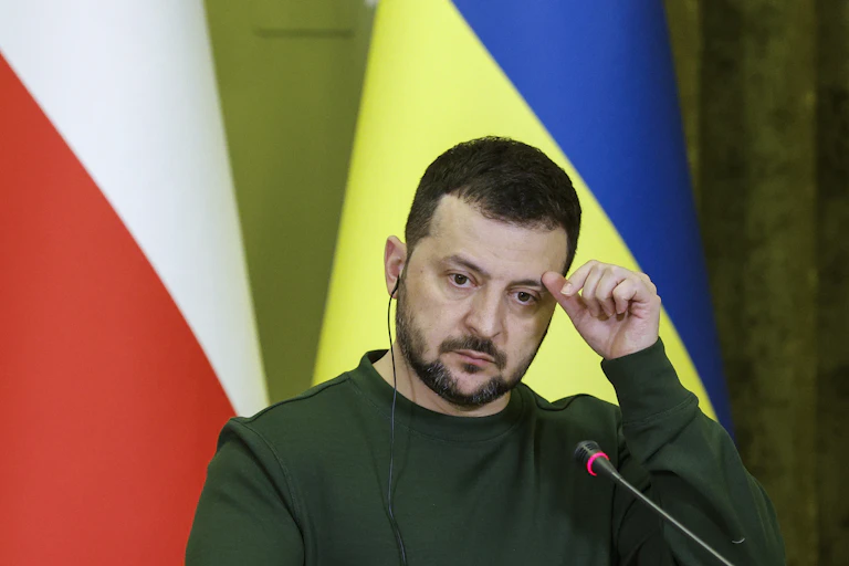 Ukrainian president, Volodymyr Zelensky, wipes his brow as he listens to press questions at a press conference, January 2024