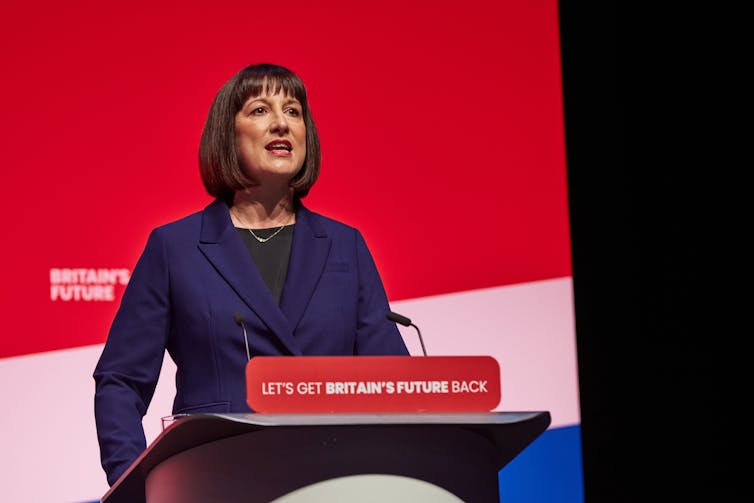 A woman at a lectern with union jack colours.